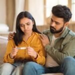 Supportive husband comforting his concerned wife holding a negative pregnancy test while seeking male infertility treatment in Delhi