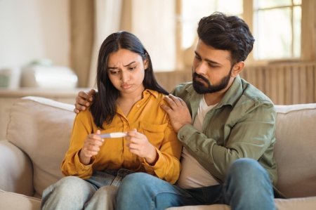 Supportive husband comforting his concerned wife holding a negative pregnancy test while seeking male infertility treatment in Delhi